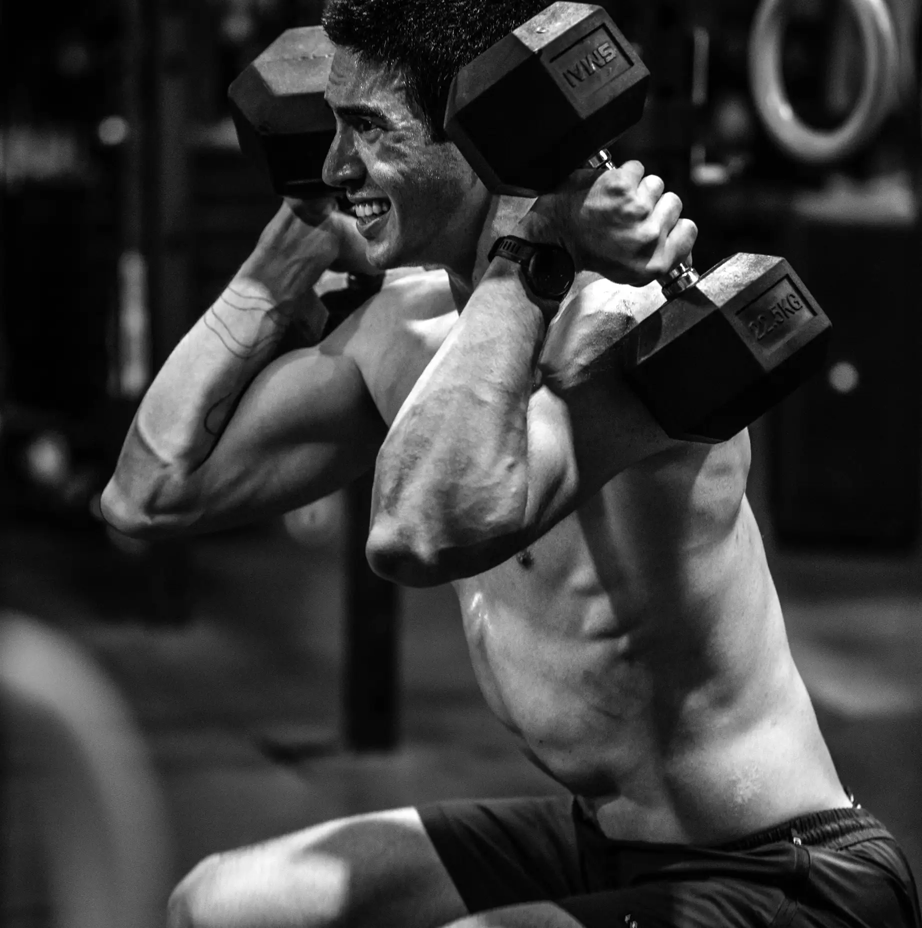 A coach guiding a member through a free-weight movement