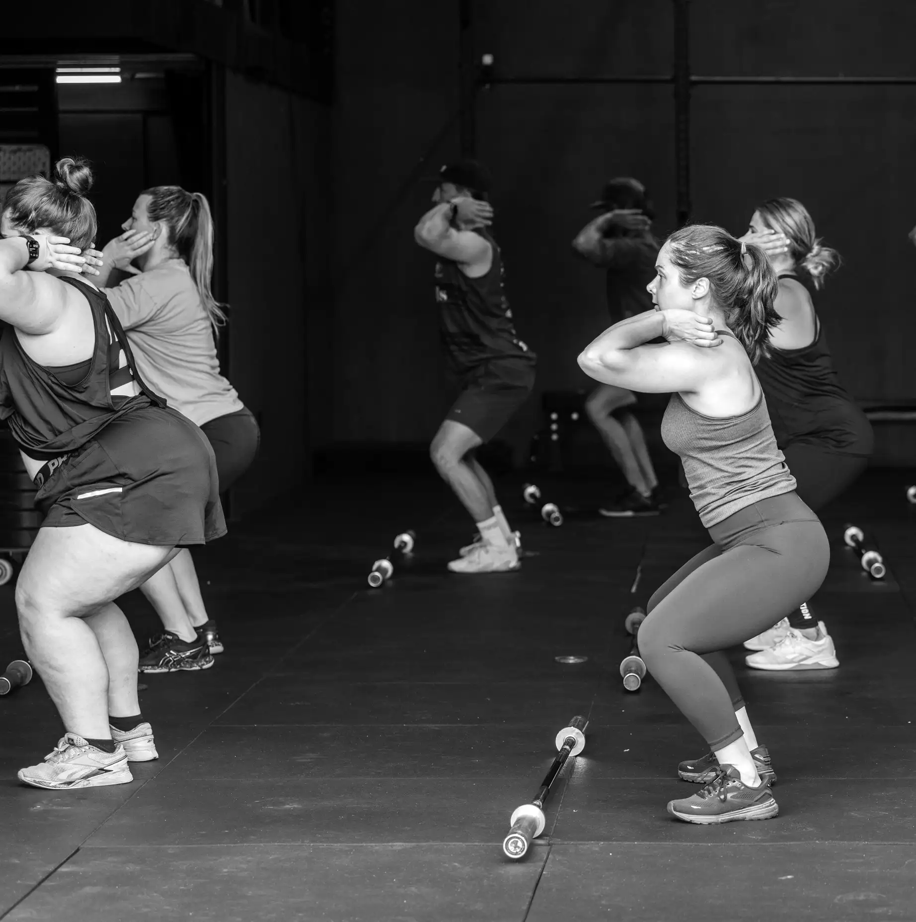 A new member learning a barbell movement one-on-one with a coach